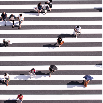 People crossing the street in a black & white stripped crosswalk.