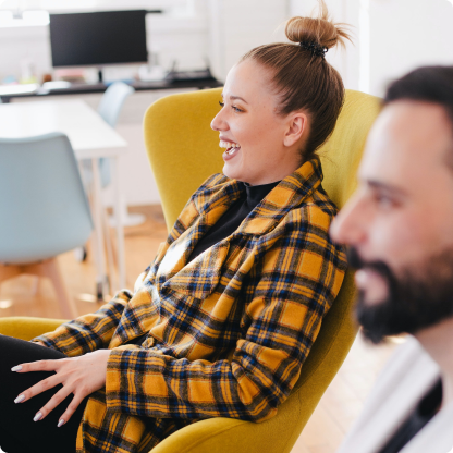 Smiling woman and man relaxing in office chairs.